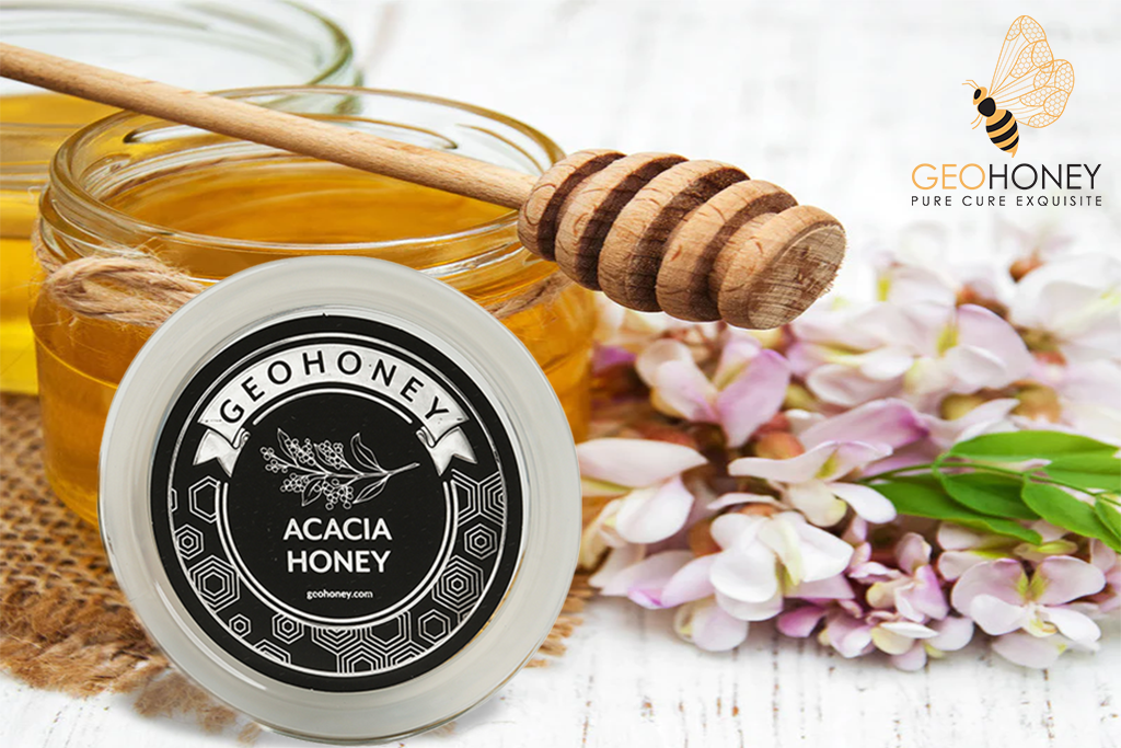 A jar of acacia honey, with a wooden honey dipper next to it.